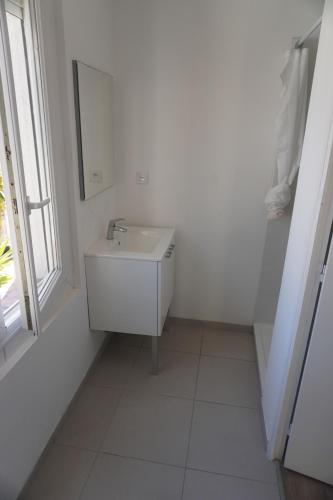 une salle de bain blanche avec un lavabo et une fenêtre dans l'établissement Résidence Clémenceau, à Port-la-Nouvelle