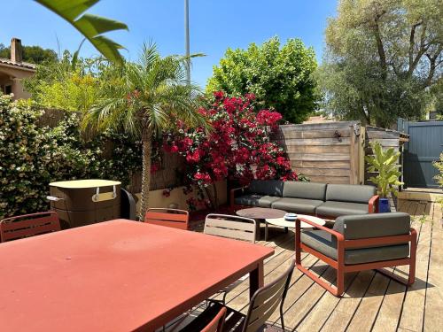 un patio avec une table et des chaises rouges et des fleurs dans l'établissement L'Ecrin, à La Ciotat