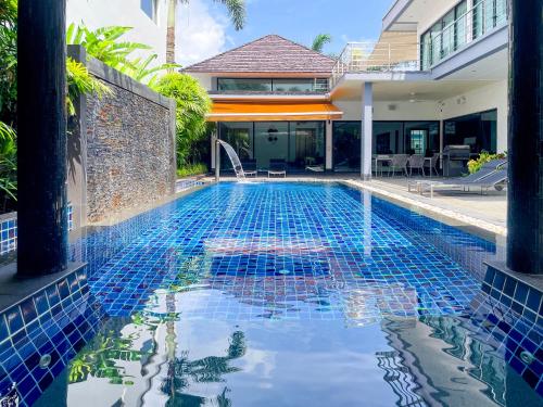 a swimming pool in front of a house at Tropical Haven Villa 4-Bedroom Private Pool Butler Choeng Thale Phuket in Bang Tao Beach