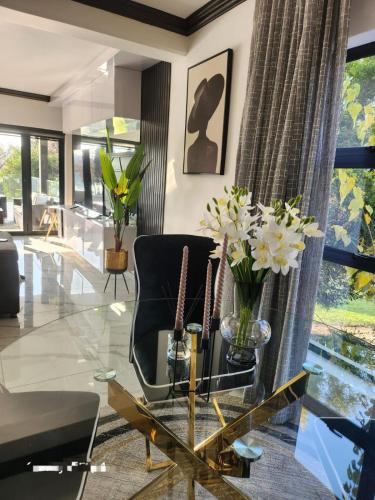 a living room with a glass table and a black chair at Gillino Vaal River Luxury Retreat in Sasolburg