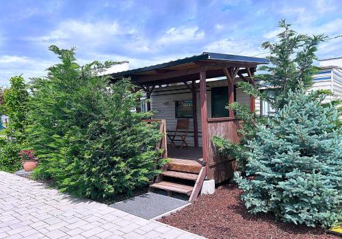 a tiny house with a wooden porch and two trees at Domčeky Nesvady in Nesvady
