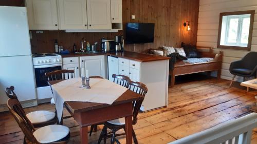 a kitchen and living room with a table and chairs at Trivelig Stabbur på Lånke Gård 