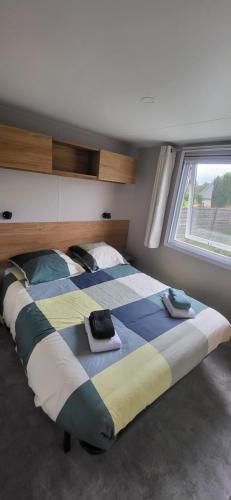 un grand lit dans une chambre avec une fenêtre dans l'établissement Mobil-home 28 m2, 2 chambres et terrasse, à Douarnenez