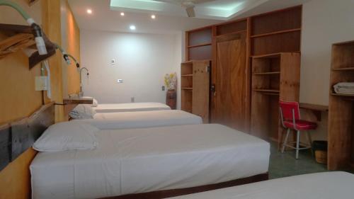 a room with four beds and a red chair at Madre Tierra Hostal in Puerto Escondido