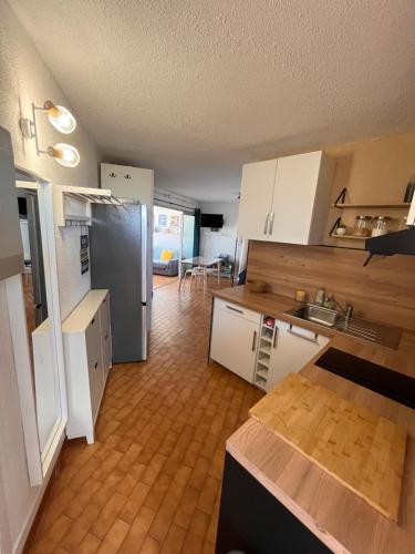 une cuisine avec des armoires blanches et un réfrigérateur en acier inoxydable dans l'établissement Evasion en Bord de Mer, au Barcarès