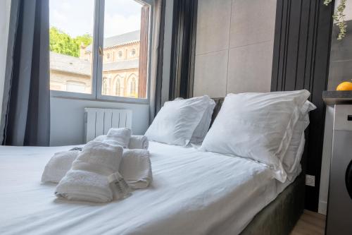 a bed with white towels on it with a window at Le Passion Room - Love Room - Jacuzzi in Beauvais