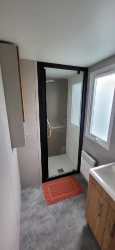La salle de bains est pourvue d'une douche et d'un miroir. dans l'établissement Mobil-home 28 m2, 2 chambres et terrasse, à Douarnenez
