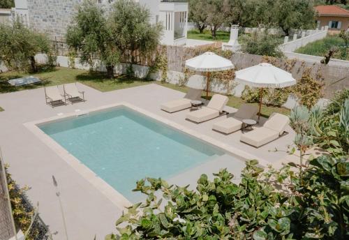 ein Bild eines Swimmingpools mit Stühlen und Sonnenschirmen in der Unterkunft SOLEIL LUXURY VILLAS in Lithakia