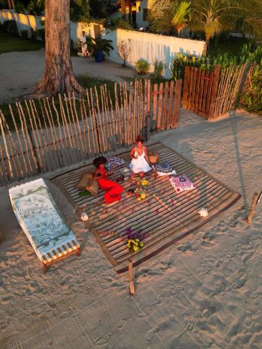 two people sitting on a blanket on the beach at MADIROKELY HOUSE Nosy Be in Ambatoloaka