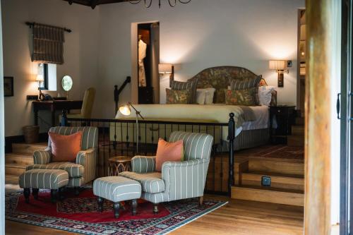 a bedroom with a bed and two chairs at Lalibela Game Reserve - Kichaka Lodge in Paterson