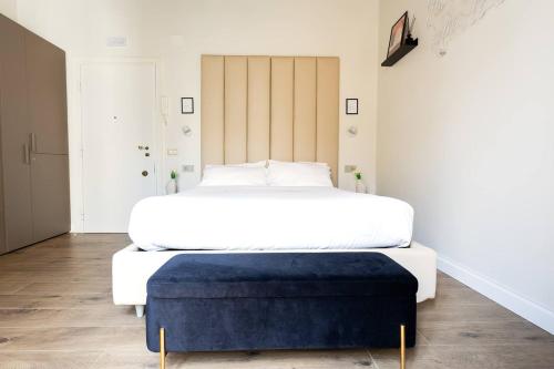 a bedroom with a large white bed and a blue ottoman at Home Sweet Rome Lucina in Rome