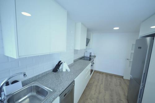 a white kitchen with a sink and a refrigerator at LA CURVA Orange Costa in Benicàssim