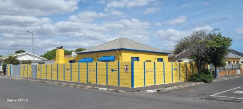 un edificio amarillo con una valla al lado de una calle en Neo & Ruks Goodwood 1, en Goodwood