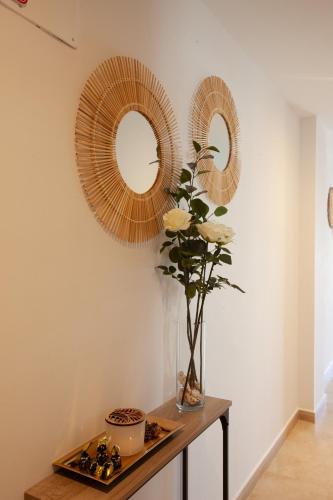 a table with two mirrors and a vase with flowers on it at El Balcón Guadalest in El Castell de Guadalest
