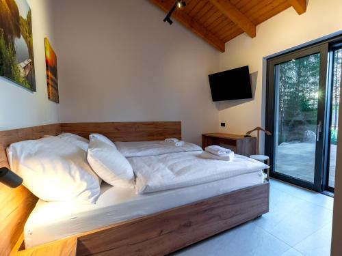 a bedroom with a large bed with white sheets at Lipno - Luxury Lake Villa in Nové Domky