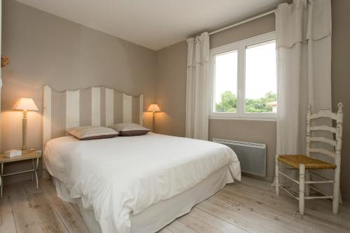 une chambre avec un grand lit blanc et une fenêtre dans l'établissement Maison calme 160m2 (1,8km plage), à Messanges