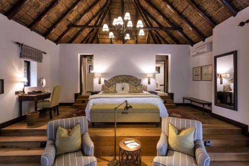 a bedroom with a bed and two chairs at Lalibela Game Reserve - Kichaka Lodge in Paterson