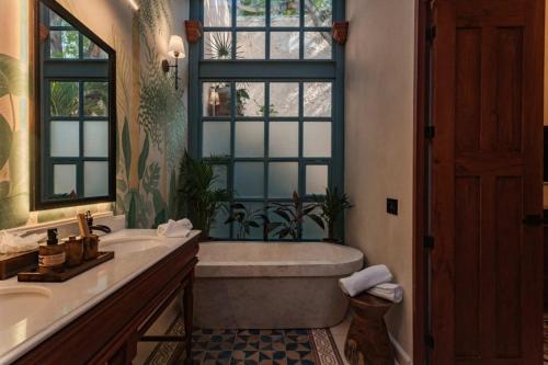 a bathroom with a tub and a sink and a window at Casa Esther - Parque Santiago in Mérida