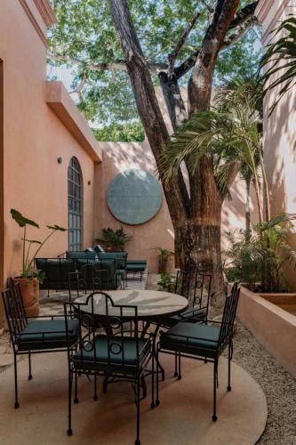 a patio with a table and chairs and a tree at Casa Esther - Parque Santiago in Mérida