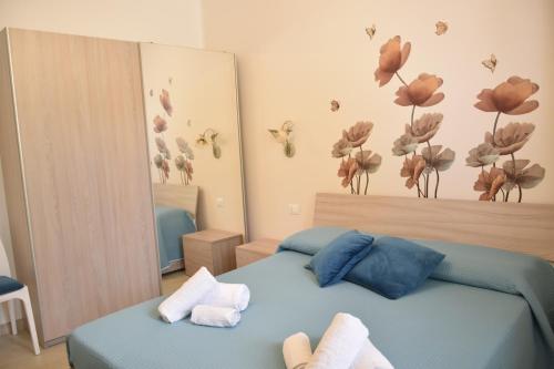 a bedroom with a blue bed and flowers on the wall at A Casuzza in Salemi