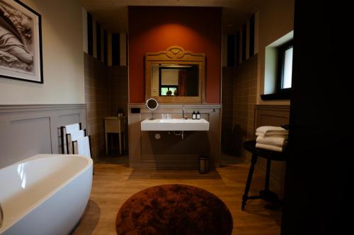 a bathroom with a sink and a tub and a mirror at Hotel Bent in Oisterwijk