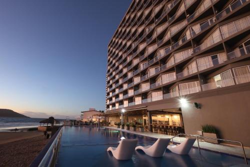 a building on the beach next to the ocean at Holiday Inn Resort Mazatlan by IHG in Mazatlán