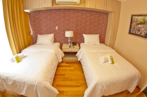 two beds in a hotel room with white sheets at Arvo Hotel Boutique in Trujillo
