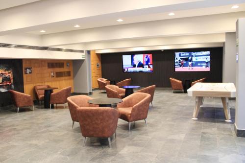 a waiting room with tables and chairs and televisions at Holiday Inn Mexico Dali Airport by IHG in Mexico City