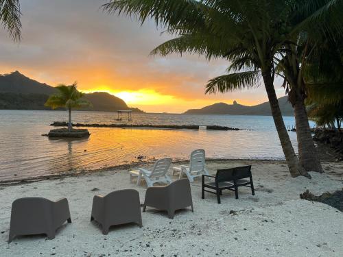 a group of chairs on a beach with a sunset at Montrose Place Huahine in HUH