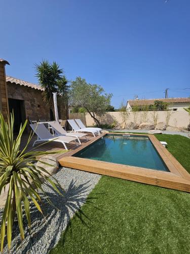 une piscine dans une cour avec des chaises et une maison dans l'établissement Maison Di Fiori, location neuve avec piscine, à Porto-Vecchio