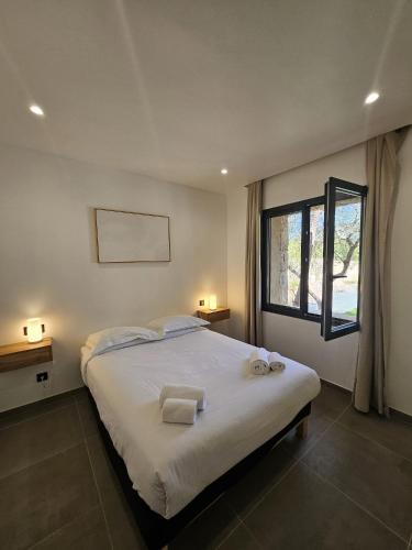 une chambre avec un grand lit avec deux serviettes dessus dans l'établissement Maison Di Fiori, location neuve avec piscine, à Porto-Vecchio