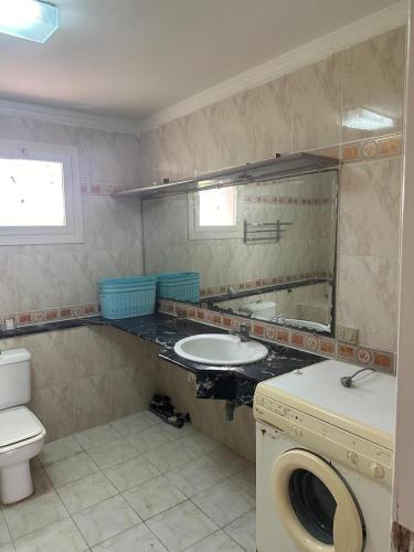 a bathroom with a sink and a toilet and a mirror at مجمع ديار بالساحل الشمالي in Sidi Kirayr