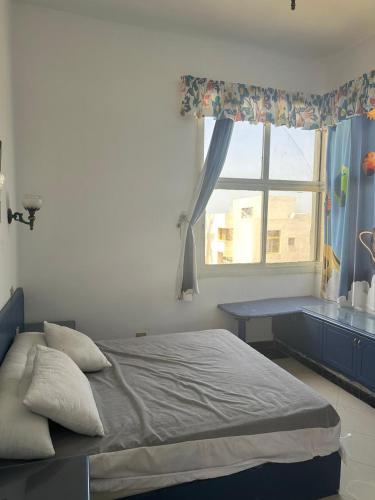 a bedroom with a bed with a window and a desk at مجمع ديار بالساحل الشمالي in Sidi Kirayr