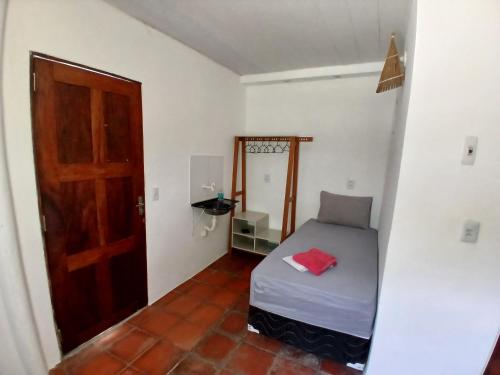 a small bedroom with a bed and a door at Pousada Unidos in Jijoca de Jericoacoara