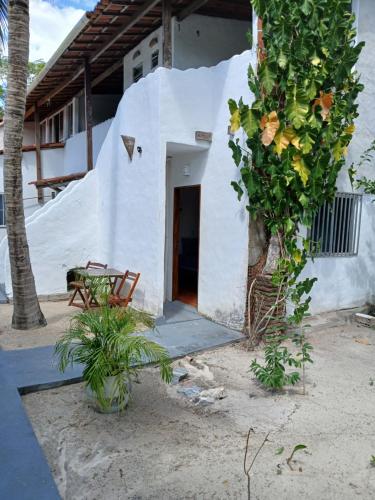 a white house with a tree in front of it at Pousada Unidos in Jijoca de Jericoacoara