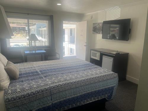 a bedroom with a bed and a flat screen tv at El Rancho Motel in Williams