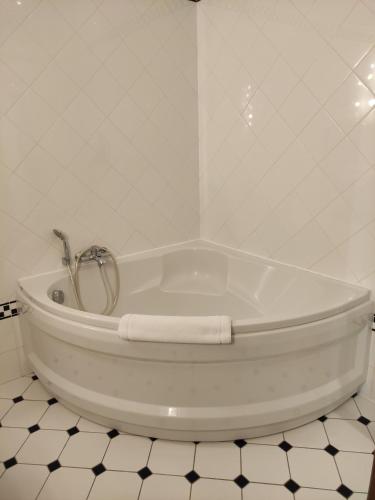 a white bath tub in a white tiled bathroom at Château De La Caze Piscine & Spa - Ste Enimie in Sainte-Énimie