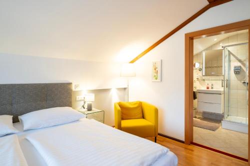 a bedroom with a bed and a yellow chair at Erlebnishaus Spiess in Feldkirchen in Kärnten