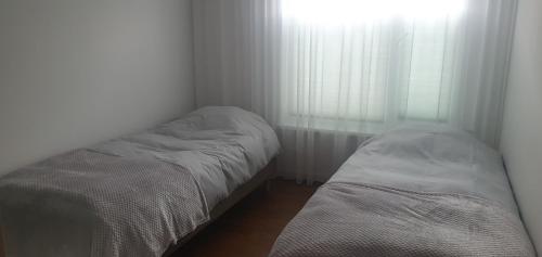 two beds in a small room with a window at Mahlamäe külaliskorter in Rapla