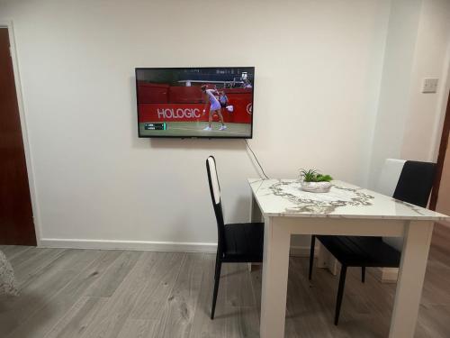 ファーナムにあるFlat in Surreyの白いテーブル(椅子付)、壁掛けテレビ