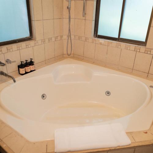 a white bath tub in a bathroom with two windows at CC Beach Front Papagayo All Inclusive in Papagayo, Guanacaste