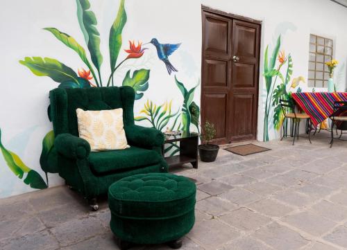 a living room with a green chair and a flower mural at Magic House Experience in Cusco