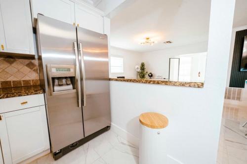 a stainless steel refrigerator in a kitchen with white cabinets at Luxe 4 BR Heated Pool - Hardrock - Stadium - Beach in Hollywood