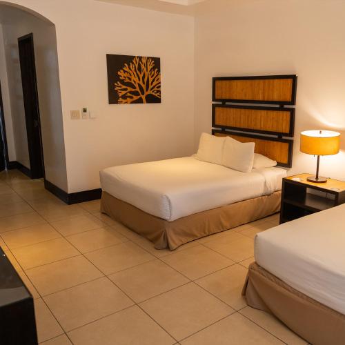 a hotel room with two beds and a lamp at CC Beach Front Papagayo All Inclusive in Papagayo, Guanacaste