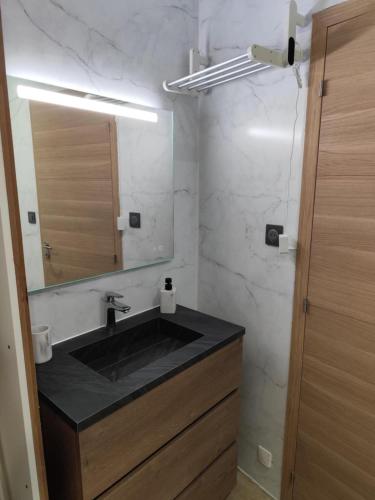 une salle de bain avec un lavabo noir et un miroir dans l'établissement Maison au cœur de saint-Lary village, à Saint-Lary-Soulan