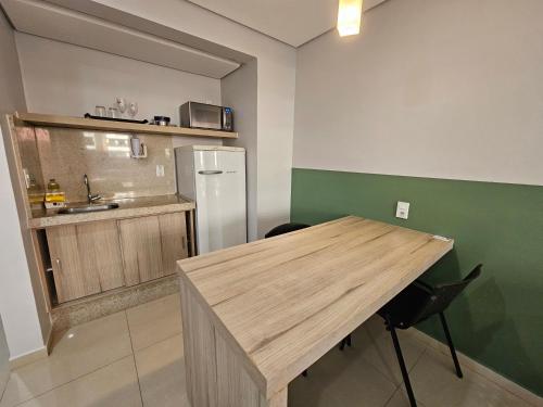 a kitchen with a wooden table and a refrigerator at ABC Apart Hotel in Brasilia