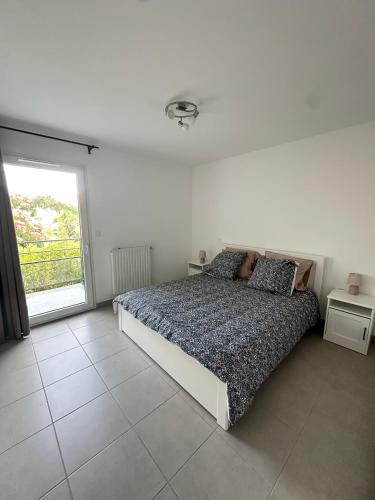 a white bedroom with a bed and a window at Maison Cosy avec Jacuzzi in Le Grau-du-Roi