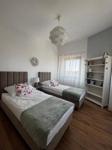 a bedroom with two beds and a chandelier at Apartament DeLux in Pasłęk
