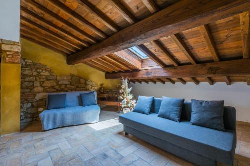 a living room with two blue couches and a wooden ceiling at Podere La Querciola in Guardistallo