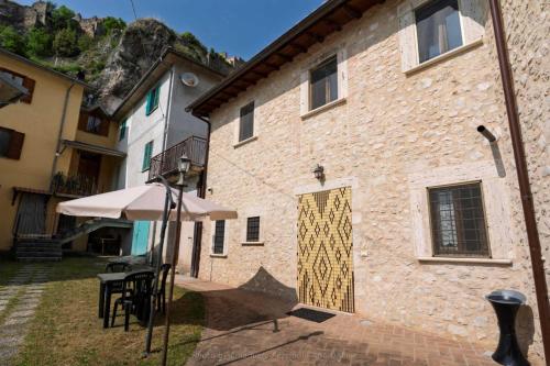 a brick building with a door with a table and an umbrella at Agriturismo Castelfranco - appartamenti Norcia in Norcia